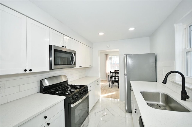 kitchen with white cabinets, sink, appliances with stainless steel finishes, and tasteful backsplash