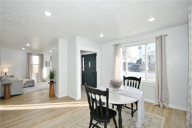 dining area with light wood-type flooring and a textured ceiling