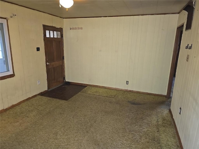 carpeted entryway with crown molding and wooden walls