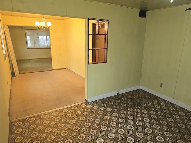 unfurnished room featuring carpet floors and an inviting chandelier