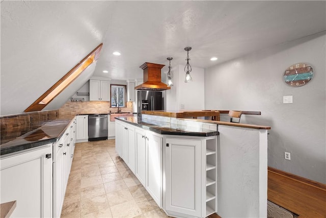 kitchen featuring a skylight, stainless steel appliances, pendant lighting, white cabinets, and a center island