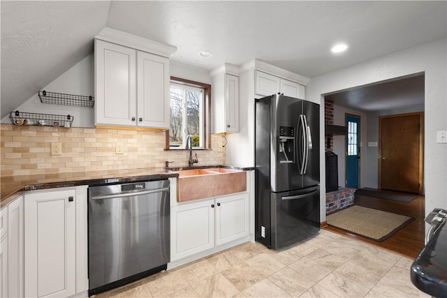 kitchen with lofted ceiling, white cabinets, sink, decorative backsplash, and appliances with stainless steel finishes