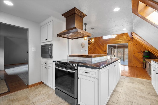 kitchen featuring premium range hood, black appliances, pendant lighting, white cabinets, and wood walls