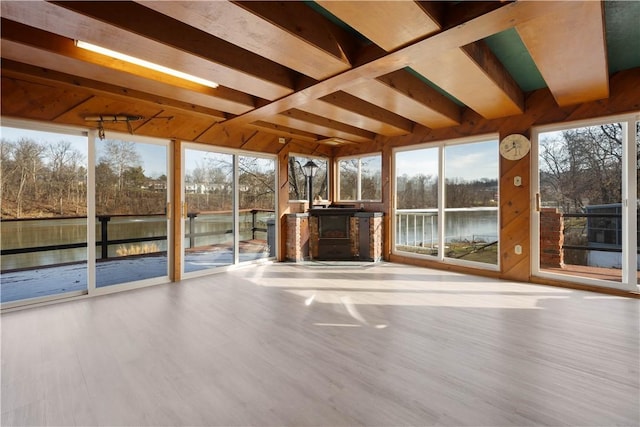 unfurnished sunroom with a wood stove and a water view