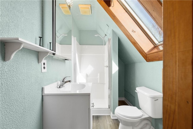 bathroom featuring hardwood / wood-style floors, a shower with door, toilet, vaulted ceiling with skylight, and vanity