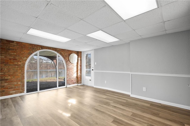 spare room with a paneled ceiling and wood-type flooring