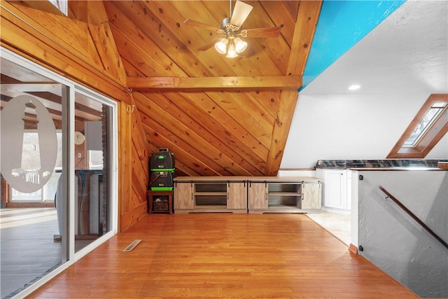 interior space featuring vaulted ceiling with skylight, ceiling fan, white cabinets, and light wood-type flooring