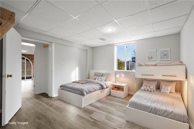 bedroom featuring a drop ceiling and light hardwood / wood-style flooring