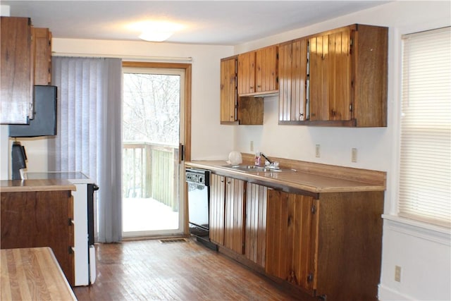 kitchen with dishwasher, sink, hardwood / wood-style floors, and range