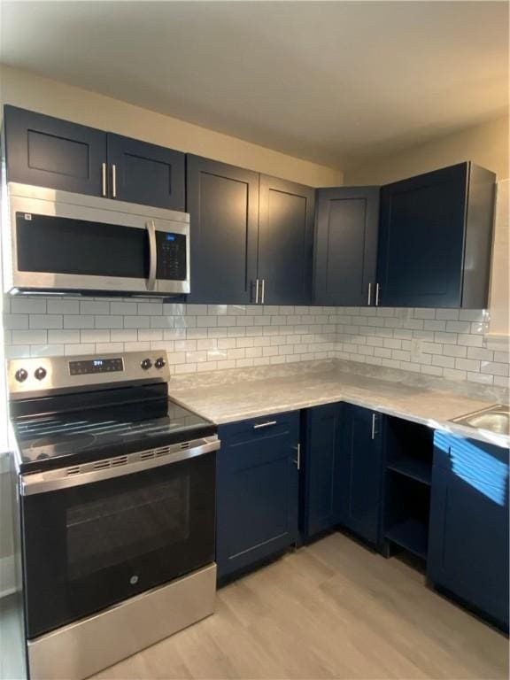 kitchen featuring decorative backsplash, sink, light wood-type flooring, and appliances with stainless steel finishes