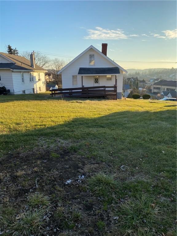 back house at dusk featuring a lawn