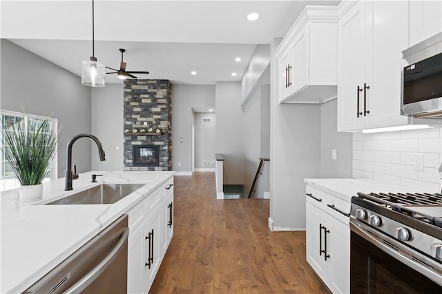 kitchen featuring white cabinets, sink, light stone countertops, appliances with stainless steel finishes, and decorative light fixtures