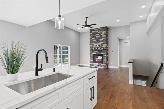 kitchen with light stone countertops, ceiling fan, sink, white cabinets, and hanging light fixtures