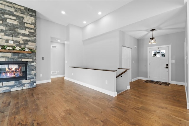 unfurnished living room with hardwood / wood-style flooring and a stone fireplace