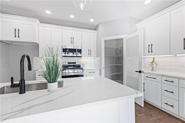 kitchen with light stone countertops, backsplash, white cabinetry, and stainless steel appliances