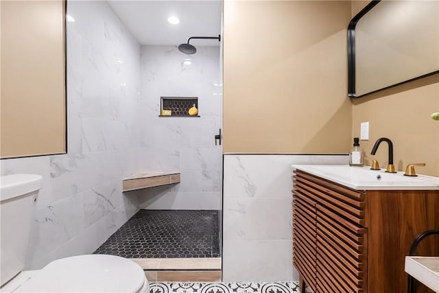 bathroom featuring a tile shower, vanity, and toilet