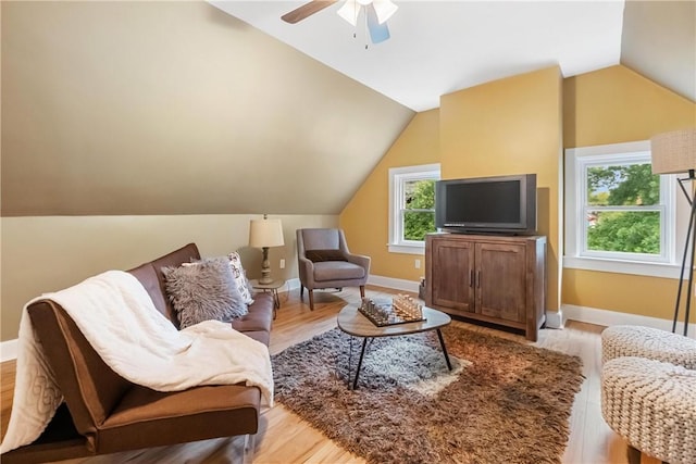 living room with ceiling fan, light hardwood / wood-style floors, and vaulted ceiling