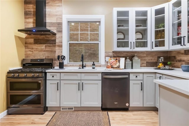 kitchen featuring sink, decorative backsplash, light wood-type flooring, stainless steel appliances, and extractor fan