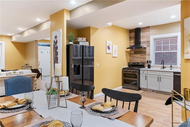 kitchen with backsplash, sink, wall chimney exhaust hood, appliances with stainless steel finishes, and white cabinetry