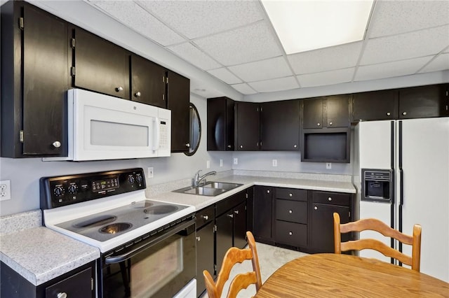 kitchen featuring white appliances, a paneled ceiling, and sink