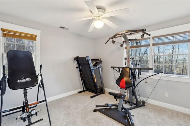 exercise area featuring ceiling fan, light colored carpet, and plenty of natural light