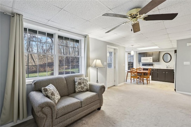 living room featuring a paneled ceiling, ceiling fan, and light carpet