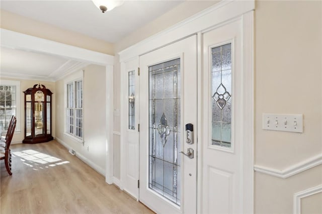 foyer entrance featuring light hardwood / wood-style floors, plenty of natural light, and ornamental molding