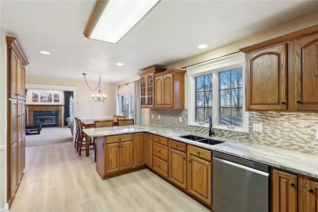 kitchen featuring sink, stainless steel dishwasher, decorative light fixtures, kitchen peninsula, and a chandelier