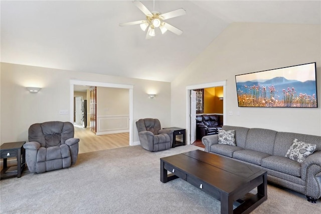 carpeted living room with ceiling fan and high vaulted ceiling