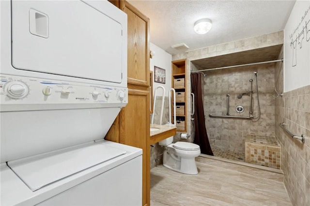 clothes washing area featuring stacked washer / dryer and a textured ceiling