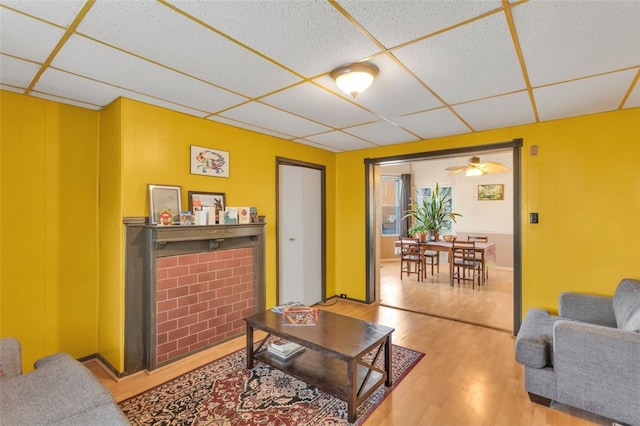 living room with a fireplace, wood-type flooring, a paneled ceiling, and ceiling fan