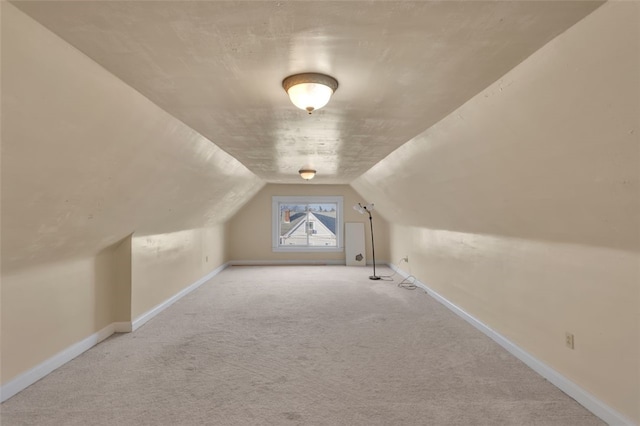 bonus room with light carpet and vaulted ceiling