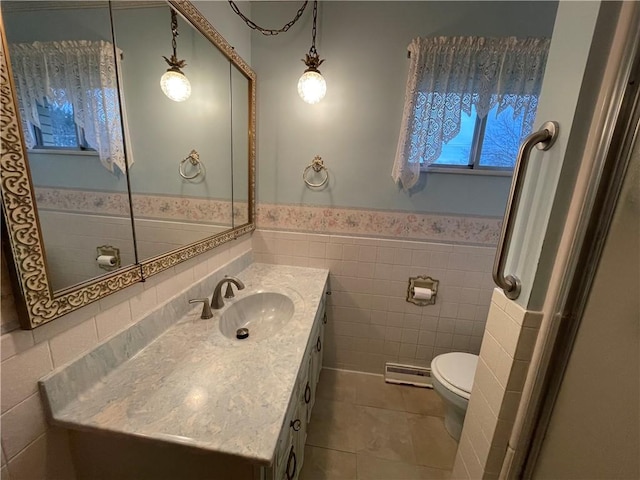 bathroom featuring vanity, tile patterned floors, toilet, tile walls, and a baseboard radiator