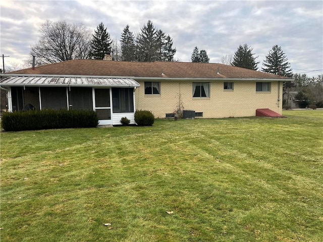 rear view of property featuring a lawn, a sunroom, and central AC unit