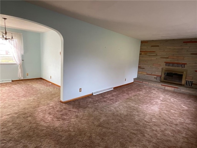 unfurnished living room with carpet flooring, a stone fireplace, baseboard heating, and an inviting chandelier