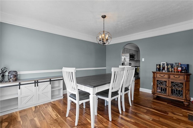 dining space with dark hardwood / wood-style flooring, ornamental molding, and an inviting chandelier