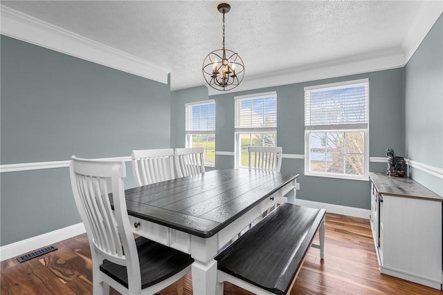 dining area with a chandelier, hardwood / wood-style floors, plenty of natural light, and ornamental molding