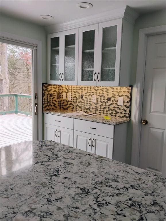 kitchen with backsplash, white cabinetry, and light stone countertops