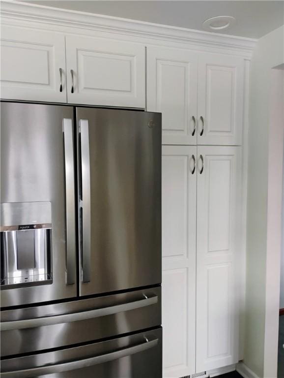 kitchen featuring stainless steel fridge and white cabinetry