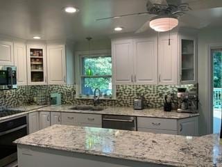 kitchen with light stone countertops, sink, white cabinets, and stainless steel appliances