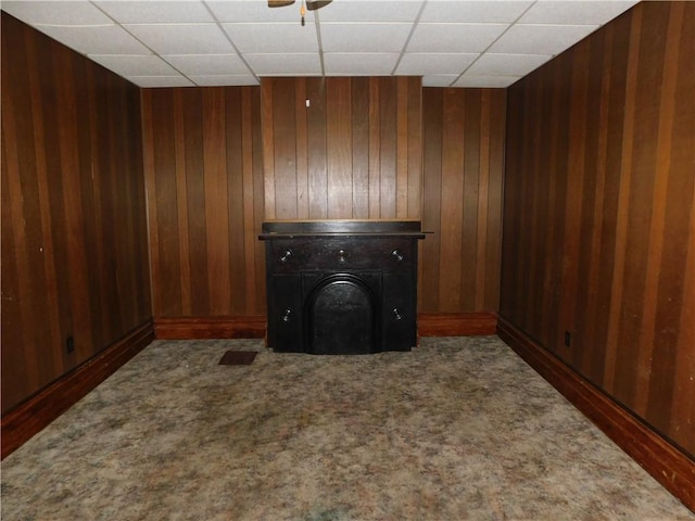 carpeted spare room with a paneled ceiling and wood walls