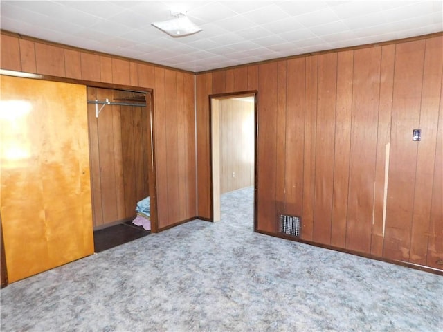 unfurnished bedroom with wood walls, a closet, and carpet floors