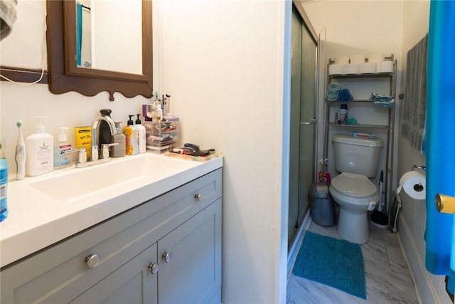 bathroom featuring vanity, a shower with shower door, and toilet