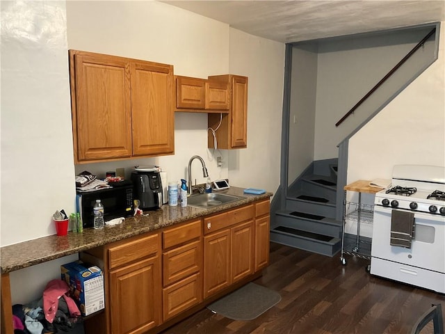 kitchen with white gas stove, dark wood-type flooring, and sink