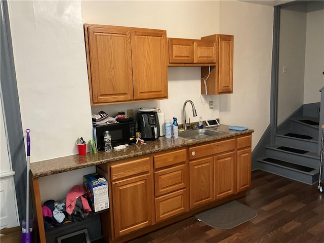 kitchen with dark hardwood / wood-style flooring, sink, and dark stone counters