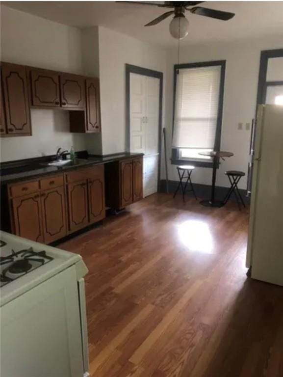 kitchen with white appliances, dark hardwood / wood-style floors, ceiling fan, and sink