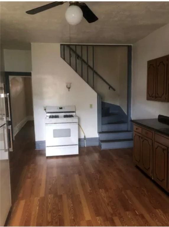 kitchen with dark hardwood / wood-style floors, ceiling fan, and white gas stove