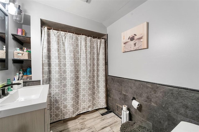 bathroom with a shower with shower curtain, hardwood / wood-style floors, vanity, and tile walls