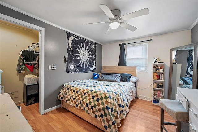 bedroom with ceiling fan, crown molding, a spacious closet, light hardwood / wood-style flooring, and a closet