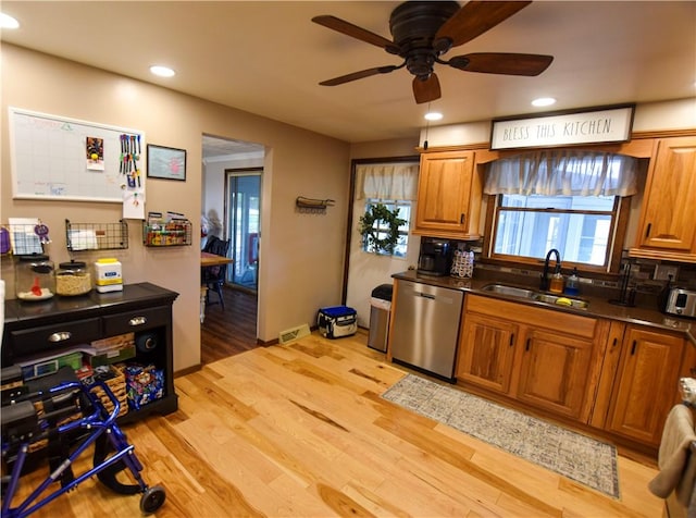 kitchen featuring light wood-type flooring, backsplash, stainless steel dishwasher, ceiling fan, and sink